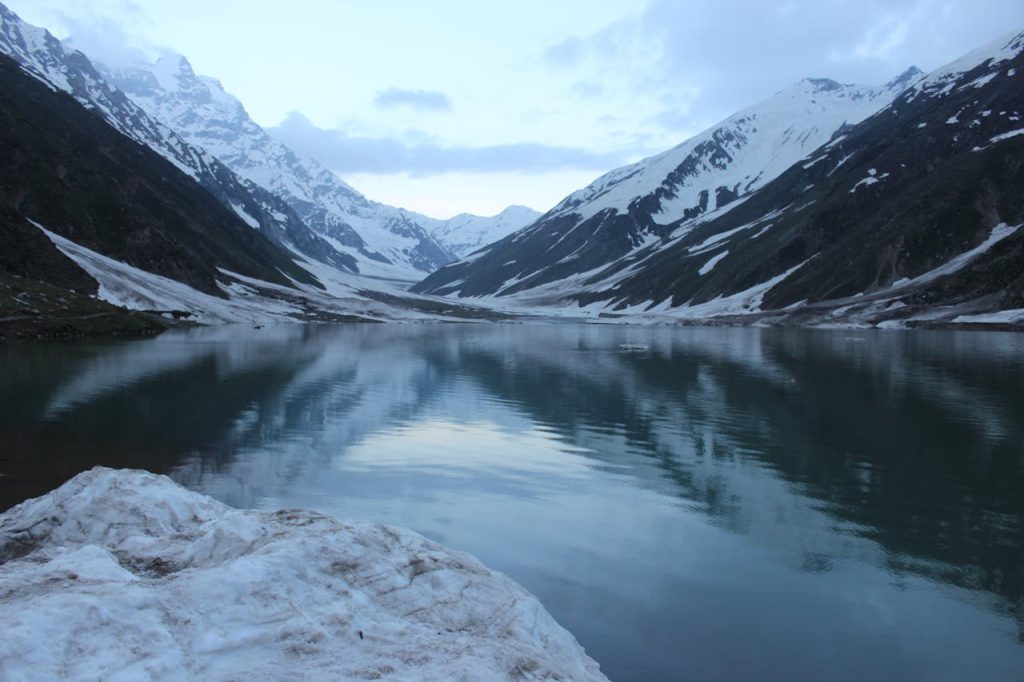 A breathtaking view of snow-covered Saif-ul-Maluk Lake surrounded by mountains in Pakistan.