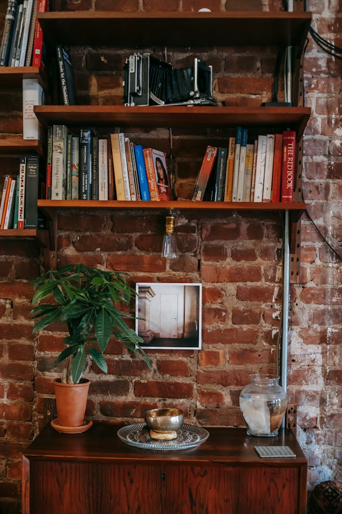 Warm and inviting home library featuring bookshelves, a brick wall, and cozy decor.